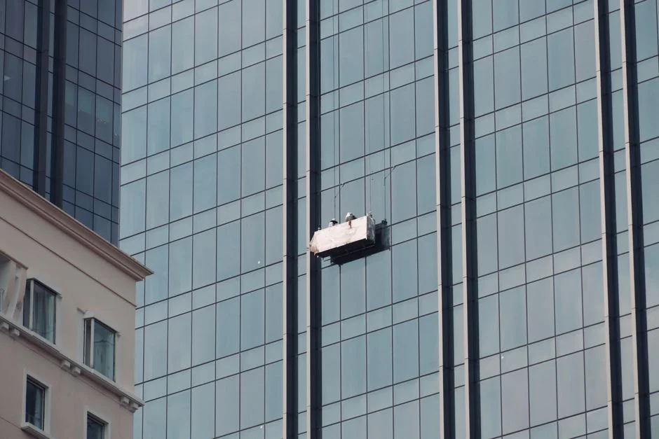 A male window cleaner washing the exterior glass roof from above with a tool during daylight.
